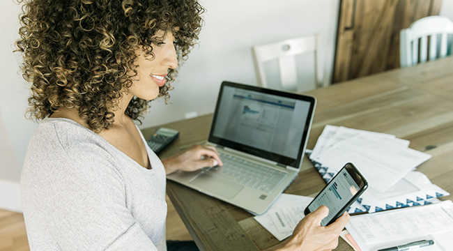 Woman using a laptop and phone.