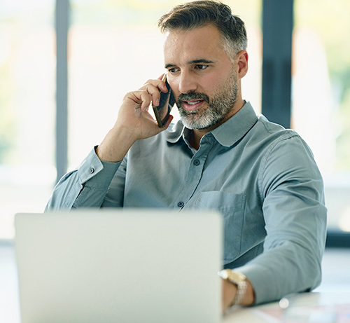 Person on phone using a laptop.