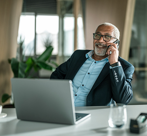 Business person using phone and a laptop.