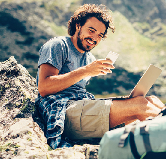 Person using their phone and a laptop.