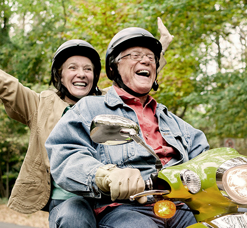 Retired couple riding on a scooter.